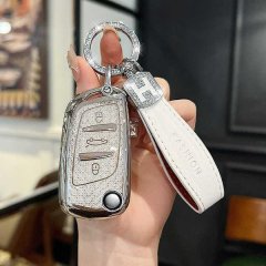 A hand holds a sleek, silver peugeot 308 key cover with a glittery finish, attached to a white leather fob labeled fashion, s...
