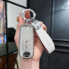 A hand holds a sleek, silver mazda cx-5 key cover for 2021+ models, featuring a textured design and a white leather strap wit...