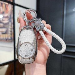 A hand holds a sleek, silver zerorun c11 key cover for 2024 models, featuring a glittery texture and a white braided lanyard.