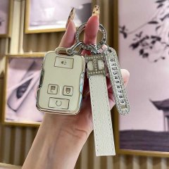 A hand holds a stylish key cover for the chevrolet suburban and gmc yukon xl, featuring a sleek design with a decorative keyc...