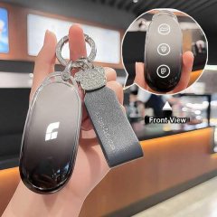 Hand holding a sleek, black ideal l9 key cover with a gradient design and decorative charm, shown from the front view in a mo...