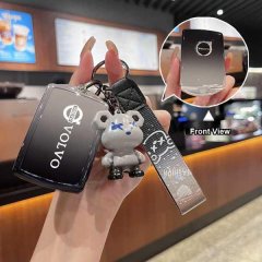 A hand holds a sleek black volvo key cover for models like the xc60, s90, and xc90, featuring a stylish bear charm and a fron...