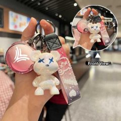 Front view of a neta v key cover featuring a cute white bear charm with blue x eyes, a pink circular keychain with a logo, an...