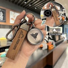 Hand holding a neta v & u pro key cover featuring a wooden tag with goodluck engraving and a sleek metallic circular design, ...