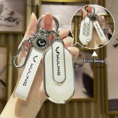 A hand holds a sleek wuling hongguang mini ev gameboy-style key cover, showcasing its front design with a white strap and met...