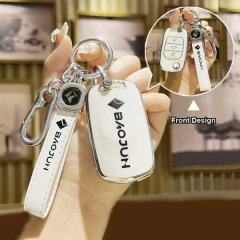 A hand holds a sleek white baojun key cover, showcasing its front design with the brand logo and a matching keychain. the ima...