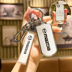 A hand holds a mazda key cover with a leather strap and carabiner, showcasing the front design of the sleek, white accessory ...