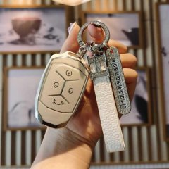 A hand holds a lynk & co 03 key cover, showcasing its sleek design with a white leather strap and decorative keychain. the sm...
