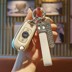 A hand holds a stylish, cream-colored buick verano key fob cover with a fold-over snap design, featuring a decorative keychai...
