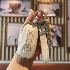 A hand holds a cream-colored aion u5/u6 key cover with a leather strap and diamond-encrusted keychain, showcasing its elegant...
