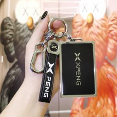 A hand holds a sleek xiaomi-powered xiao peng p7 key cover, featuring a black leather strap with peng text and a metallic tag...