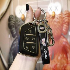 A hand holds a sleek black cadillac ct5 key cover with gold accents, featuring a genuine leather strap and a matching keychai...