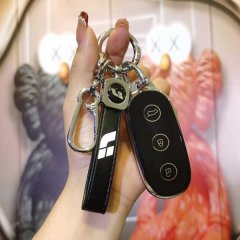 A hand holds a sleek black key cover for ideal l9, l8, l7, and ideal one ev keys, featuring a modern design with a carabiner ...