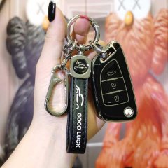 A hand holds a sleek black ds master car key cover for kd modded keys, featuring a good luck strap and a carabiner, set again...