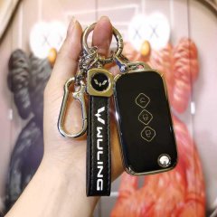 A hand holds a sleek wuling xingchen key cover, featuring a black leather strap with wuling text and a metallic carabiner, de...