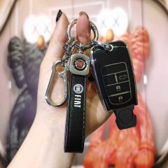 A hand holds a fiat ottimo key cover, featuring genuine leather with a sleek black design and a carabiner clip, set against a...