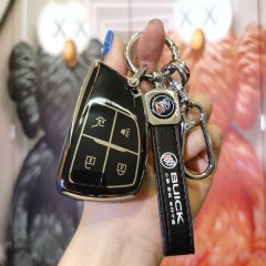 A hand holds a sleek black leather key cover for the buick enclave plus 2022, featuring a glossy finish and a matching keycha...