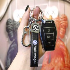 A hand holds a sleek volkswagen jetta x8 plus key cover, featuring a black leather strap with the vw logo and a matching key ...