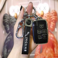 A hand holds a sleek jaguar key cover with a leather strap and metal fob, designed for f-pace, xe, and xj models, offering pr...