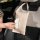 A beige diy leather car tissue box hangs on a seat back, featuring a quilted design and a convenient front pocket for easy ac...