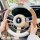 A person holds a car steering wheel covered with a lamb wool cartoon design, featuring soft beige and white textures for warm...