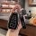 A hand holds a sleek black geely emgrand key cover with a silver trim, featuring buttons for car functions and a (pingsan)...