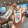 Hand holding a bmw 5 series car key cover featuring a doraemon design with a matching keychain, set in a cozy café environmen...