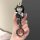 A hand holds a stylish black key cover featuring a cartoon character with bunny ears, holding a small bear, designed for aima...
