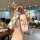 A hand holds a stylish gac aion y plus key cover featuring a white and black checkered strap and a beige case with and ...