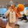 A hand holds a stylish roewe rx5 plus key cover with a good luck design, accompanied by a knitted orange tag and a small deco...