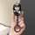A hand holds a stylish gac aion v key cover featuring a cartoon character in a black outfit with a hat, designed for ut aion ...