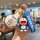 A hand holds a doraemon-themed keychain featuring a blue strap, a 3d doraemon figure, and a leather shell case with a doraemo...
