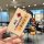 A hand holds a beige xpeng mona m03 key fob cover featuring japanese-style blessings like and , adorned with a cute ra...