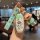 Hand holding a li auto l9 key cover featuring a cartoon design with a matching keychain, set in a cozy café ambiance.