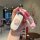 A hand holds a white jeep car key cover featuring a cute pink bunny design, attached to a pink and white braided lanyard, sui...