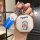 A hand holds a doraemon-themed car key cover with a blue and white design, featuring the iconic character on a metallic octag...