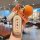 A hand holds a huawei aito m7 car key cover with a decorative orange and white knitted charm, featuring the text everything w...