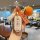 A hand holds a huawei aito m7 car key cover featuring a white and orange design with text, accompanied by a knitted orange...