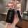 A hand holds a sleek black wuling xingguang car key cover with silver accents, featuring three buttons and a pingan charm, se...