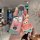 A hand holds a lexus key cover featuring patrick star from spongebob, paired with a matching keychain charm, set in a cozy ca...