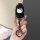 A hand holds a sleek black gac gs4 car key cover featuring a white hello kitty design, complete with a shiny metallic key rin...