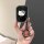 A hand holds a sleek black lynk & co 06 car key cover featuring a white hello kitty design with a bow, attached to a shiny me...