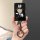 A hand holds a sleek black xiaomi su7 card key cover featuring a cute panda design with a hat and bow, attached to a shiny ke...