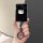 A hand holds a sleek black car key cover featuring a white hello kitty design, attached to a stylish keychain with a circular...