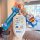 Hand holding a doraemon-themed key cover for gac trumpchi vehicles, featuring a white case with cartoon designs and a blue ke...