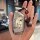 A hand holds a sleek, metallic key cover featuring a cartoon design with the text and a small black figurine attache...