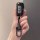 A hand holds a sleek black nissan key fob with a transparent shell case, featuring lock, unlock, and panic buttons, attached ...