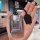 A hand holds a sleek, metallic car key cover featuring a cartoon bear design and chinese text, paired with a black leather ta...