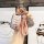 A hand holds a stylish pink wuling hongguang mini ev key cover with a braided strap and decorative charms, set against a mode...