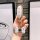 A hand holds a stylish ideal l8 key cover, featuring a white leather design with gold accents and a decorative butterfly char...